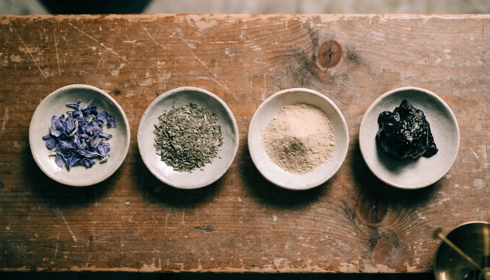Ceramic dishes showing blue lotus petals, dried kanna herb, extract powder and resin